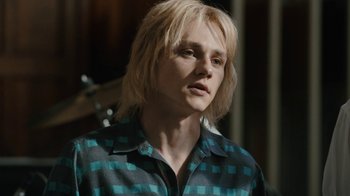 Movie still from “Bohemian Rhapsody” (2018), directed by Bryan Singer – A man with blonde hair wearing a checkered shirt; Close Up shot, Low angle