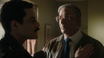 Movie still from “Bohemian Rhapsody” (2018), directed by Bryan Singer – An older man wearing glasses and a tie talking to a younger man; Close Up shot, Over the shoulder angle