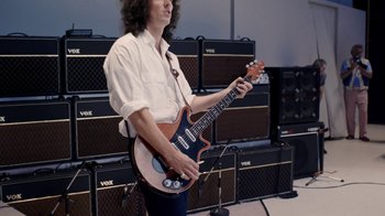 Movie still from “Bohemian Rhapsody” (2018), directed by Bryan Singer – A man holding an electric guitar in front of a bunch of amps; Medium shot, High angle