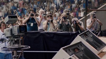 Movie still from “Bohemian Rhapsody” (2018), directed by Bryan Singer – A group of people taking pictures in front of an audience; Wide shot, High angle