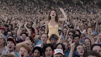 Movie still from “Bohemian Rhapsody” (2018), directed by Bryan Singer – A woman is sitting on the shoulders of a crowd of people; Wide shot, High angle