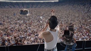 Movie still from “Bohemian Rhapsody” (2018), directed by Bryan Singer – A man in a white tank top is on a stage; Extreme Wide shot, High angle