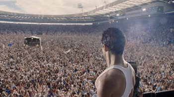 Movie still from “Bohemian Rhapsody” (2018), directed by Bryan Singer – A man standing in front of a crowd at a concert; Extreme Wide shot, High angle