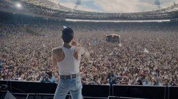 Movie still from “Bohemian Rhapsody” (2018), directed by Bryan Singer – A man in a white tank top is on a stage in front of a crowd; Extreme Wide shot, High angle