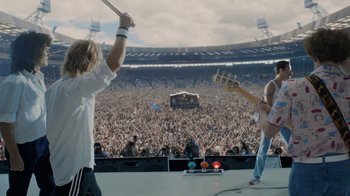Movie still from “Bohemian Rhapsody” (2018), directed by Bryan Singer – Two people on a stage in front of an audience; Wide shot, High angle