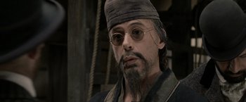 Movie still from “Sherlock Holmes: A Game of Shadows” (2011), directed by Guy Ritchie – A person with a beard wearing a hat; Close Up shot, Over the shoulder angle