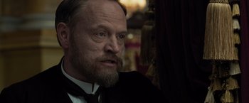 Movie still from “Sherlock Holmes: A Game of Shadows” (2011), directed by Guy Ritchie – A person with a beard wearing a suit; Close Up shot, Over the shoulder angle