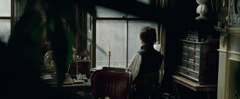 Movie still from “Sherlock Holmes: A Game of Shadows” (2011), directed by Guy Ritchie – A man sitting in front of a window looking outside; Medium shot, Over the shoulder angle