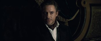 Movie still from “Sherlock Holmes: A Game of Shadows” (2011), directed by Guy Ritchie – A person wearing a suit and tie; Close Up shot, Over the shoulder angle