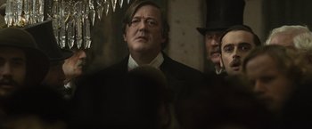 Movie still from “Sherlock Holmes: A Game of Shadows” (2011), directed by Guy Ritchie – A man in a suit and a hat is standing next to another man in a hat; Close Up shot, Over the shoulder angle