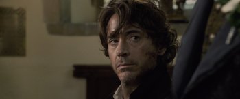Movie still from “Sherlock Holmes: A Game of Shadows” (2011), directed by Guy Ritchie – A person wearing a black shirt; Close Up shot, Over the shoulder angle