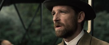 Movie still from “Sherlock Holmes: A Game of Shadows” (2011), directed by Guy Ritchie – A person with a beard wearing a hat; Close Up shot, Over the shoulder angle