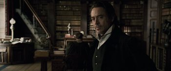 Movie still from “Sherlock Holmes: A Game of Shadows” (2011), directed by Guy Ritchie – A man standing in front of a book shelf; Medium shot, Over the shoulder angle