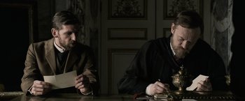 Movie still from “Sherlock Holmes: A Game of Shadows” (2011), directed by Guy Ritchie – Two men sitting at a table in front of a book; Medium shot, Over the shoulder angle