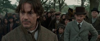 Movie still from “Sherlock Holmes: A Game of Shadows” (2011), directed by Guy Ritchie – A crowd of people wearing hats and coats; Close Up shot, Over the shoulder angle