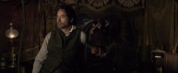 Movie still from “Sherlock Holmes: A Game of Shadows” (2011), directed by Guy Ritchie – A man sitting in front of a mirror in a dark room; Medium shot, Over the shoulder angle