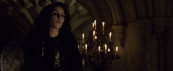 Movie still from “Sherlock Holmes: A Game of Shadows” (2011), directed by Guy Ritchie – A woman standing in front of a chandelier in a dark room; Medium shot, Low angle