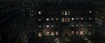 Movie still from “Sherlock Holmes: A Game of Shadows” (2011), directed by Guy Ritchie – A large building with many windows lit up at night; Extreme Wide shot, High angle