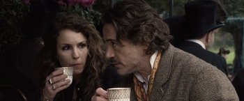 Movie still from “Sherlock Holmes: A Game of Shadows” (2011), directed by Guy Ritchie – A man and a woman sitting next to each other holding a mug; Close Up shot, Over the shoulder angle