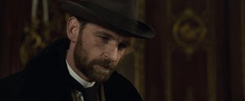 Movie still from “Sherlock Holmes: A Game of Shadows” (2011), directed by Guy Ritchie – A man with a beard wearing a hat and a tie; Close Up shot, Over the shoulder angle