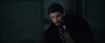 Movie still from “Sherlock Holmes: A Game of Shadows” (2011), directed by Guy Ritchie – A person wearing a suit and tie; Close Up shot, Over the shoulder angle