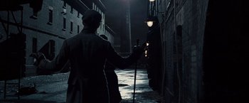 Movie still from “Sherlock Holmes: A Game of Shadows” (2011), directed by Guy Ritchie – A man holding a cane walking down a street; Wide shot, Low angle