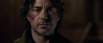 Movie still from “Sherlock Holmes: A Game of Shadows” (2011), directed by Guy Ritchie – A person with a bruise on his face; Close Up shot, Over the shoulder angle