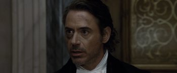 Movie still from “Sherlock Holmes: A Game of Shadows” (2011), directed by Guy Ritchie – A person wearing a suit and tie; Close Up shot, Over the shoulder angle