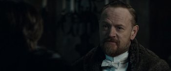 Movie still from “Sherlock Holmes: A Game of Shadows” (2011), directed by Guy Ritchie – A man with a goatee and a beard wearing a white bow tie; Close Up shot, Over the shoulder angle