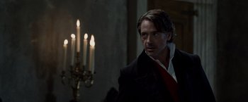 Movie still from “Sherlock Holmes: A Game of Shadows” (2011), directed by Guy Ritchie – A person wearing a suit near candles; Close Up shot, Over the shoulder angle