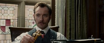 Movie still from “Sherlock Holmes: A Game of Shadows” (2011), directed by Guy Ritchie – A man in a suit and tie holding a wooden spoon; Close Up shot, Low angle