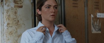 Movie still from “Sheroes” (2023), directed by Jordan Gertner – A woman putting on a button up shirt; Close Up shot, Over the shoulder angle