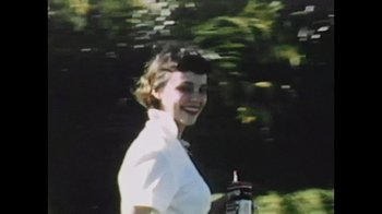 Movie still from “Sheryl” (2022), directed by Amy Scott – A woman in a white shirt is smiling for the camera; Close Up shot, Low angle
