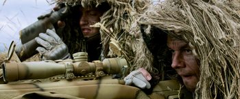 Movie still from “Shooter” (2007), directed by Antoine Fuqua – A man in a ghillie suit with a rifle; Close Up shot, Over the shoulder angle