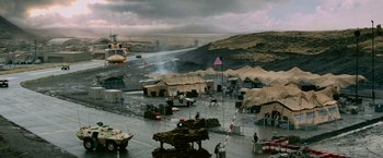 Movie still from “Shooter” (2007), directed by Antoine Fuqua – An american flag flies in front of tents and a helicopter; Extreme Wide shot, High angle