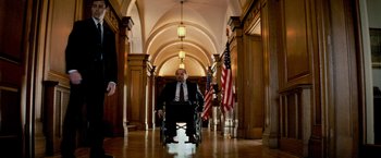 Movie still from “Shooter” (2007), directed by Antoine Fuqua – A man in a suit in a wheel chair in a hallway; Wide shot, Low angle
