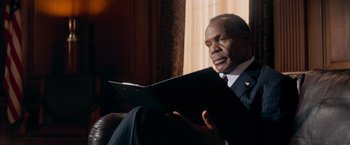 Movie still from “Shooter” (2007), directed by Antoine Fuqua – A man in a suit and tie holding a book; Close Up shot, Low angle