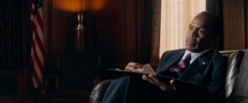 Movie still from “Shooter” (2007), directed by Antoine Fuqua – A person sitting in a chair holding an open book; Close Up shot, Over the shoulder angle