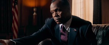 Movie still from “Shooter” (2007), directed by Antoine Fuqua – A man in a suit and tie sitting in a chair; Close Up shot, Low angle