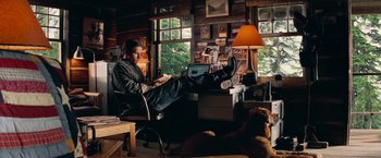 Movie still from “Shooter” (2007), directed by Antoine Fuqua – A man sitting at a desk with his feet on the desk; Wide shot, Low angle