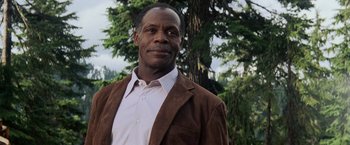 Movie still from “Shooter” (2007), directed by Antoine Fuqua – A man wearing a brown jacket standing in front of a tree; Close Up shot, Low angle