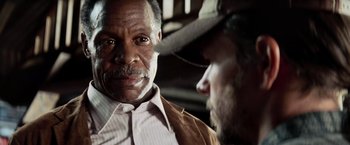 Movie still from “Shooter” (2007), directed by Antoine Fuqua – A man with a beard and a hat is talking to another man; Close Up shot, Over the shoulder angle