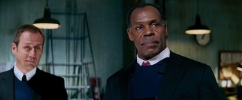 Movie still from “Shooter” (2007), directed by Antoine Fuqua – An older man in a suit and red tie; Close Up shot, Low angle