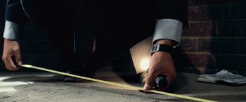 Movie still from “Shooter” (2007), directed by Antoine Fuqua – A man holding a tape measure in his hand; Extreme Close Up shot, Overhead angle