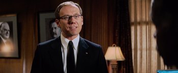 Movie still from “Shooter” (2007), directed by Antoine Fuqua – A man in a suit and tie standing in front of a lamp; Close Up shot, Low angle
