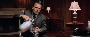 Movie still from “Shooter” (2007), directed by Antoine Fuqua – A man in a suit pouring wine into a wine glass; Close Up shot, Low angle