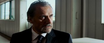 Movie still from “Shooter” (2007), directed by Antoine Fuqua – An older man wearing a suit and tie looking at the camera; Close Up shot, Low angle