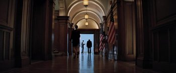 Movie still from “Shooter” (2007), directed by Antoine Fuqua – Two people are standing in a hallway with american flags; Extreme Wide shot, Low angle