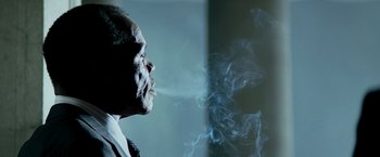 Movie still from “Shooter” (2007), directed by Antoine Fuqua – An older man smoking a cigarette in front of a wall; Close Up shot, Low angle