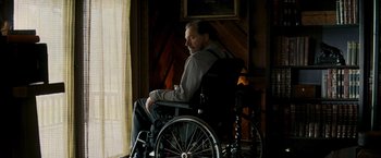 Movie still from “Shooter” (2007), directed by Antoine Fuqua – A man sitting in a wheel chair looking out a window; Medium shot, Low angle